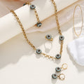 Bohemian style gold-tone evil eye necklace, bracelet, and earring jewelry set on a neutral background.