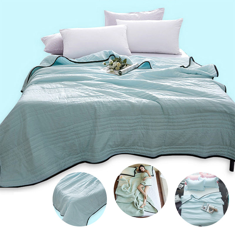 A modern, minimalist pastel mint-green cooling quilt with black edge binding draped over a clean white bed.