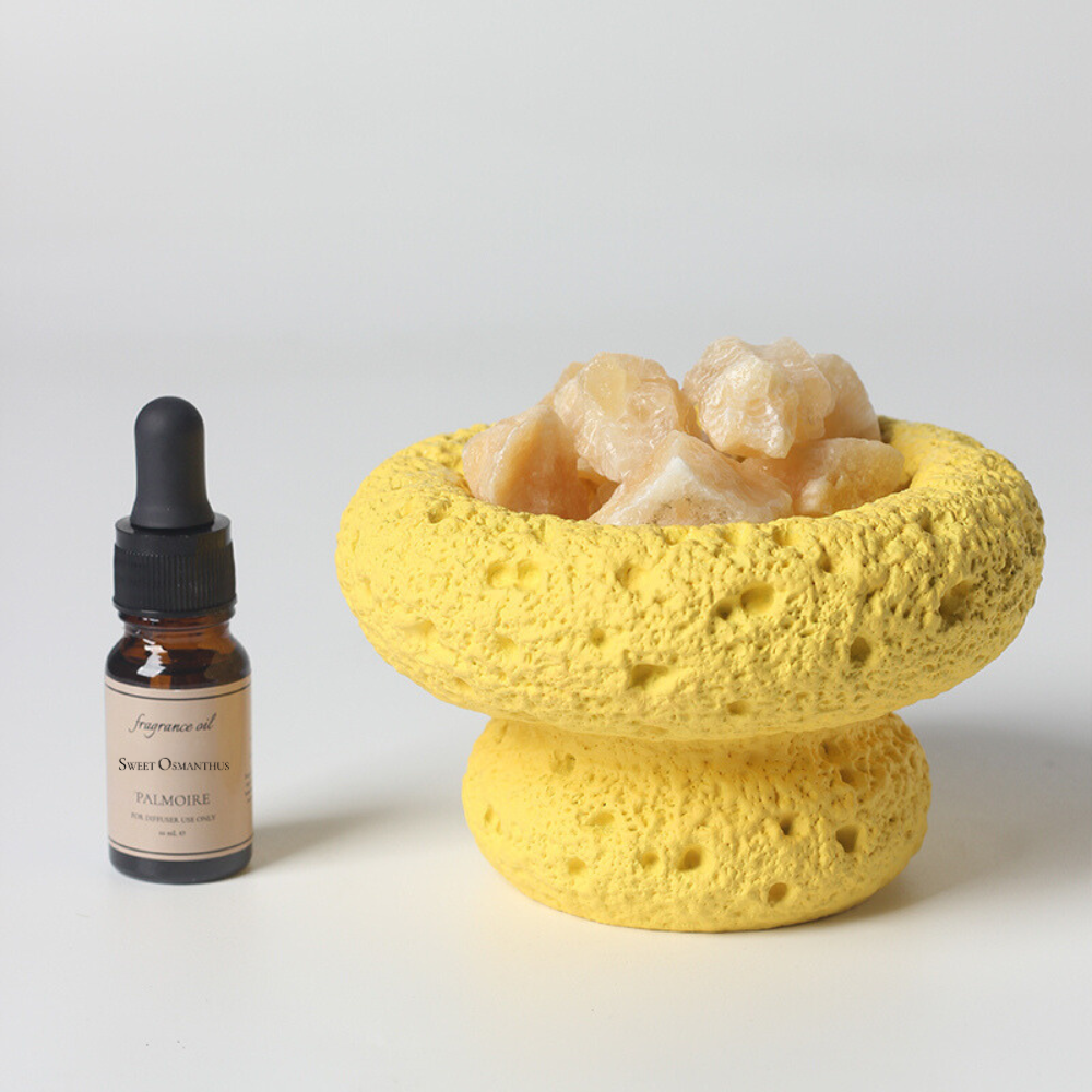 Yellow moon-shaped stone diffuser set with a bottle of Sweet Osmanthus fragrance oil on a white background