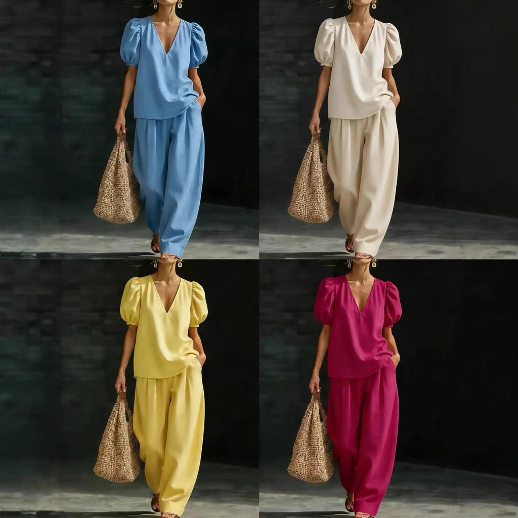 A woman wearing a matching two-piece set featuring a V-neck top with puff sleeves and wide-leg trousers in a solid color.