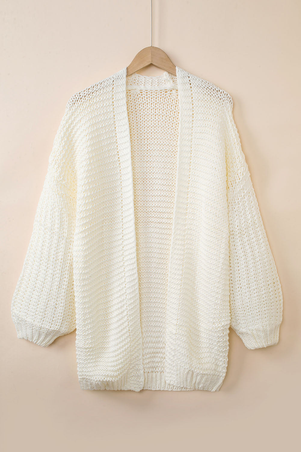 Front and back view of a cream colored chunky knit cardigan with puff sleeves hanging on a wooden hanger