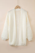 Front and back view of a cream colored chunky knit cardigan with puff sleeves hanging on a wooden hanger
