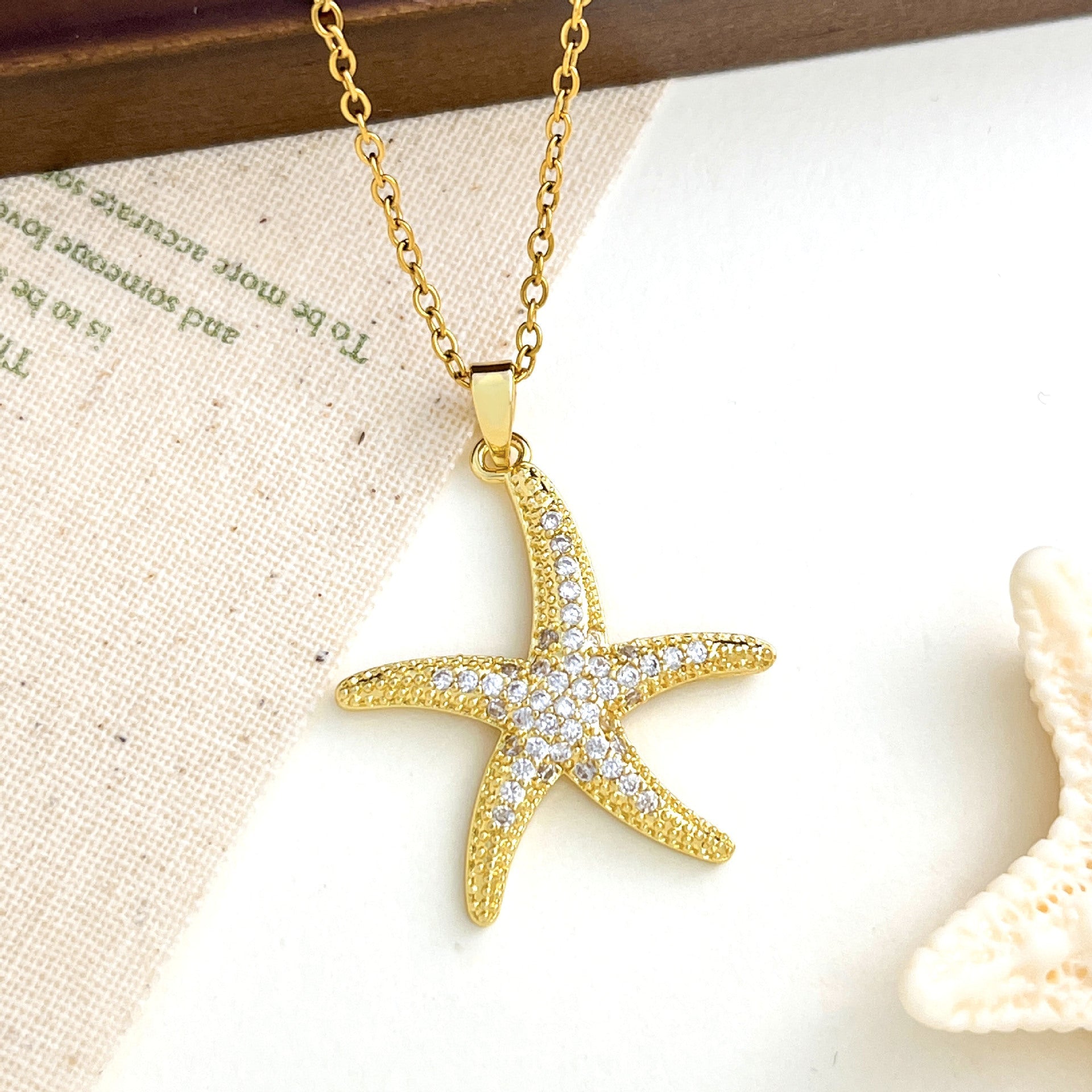 Gold starfish pendant necklace with pave-set cubic zirconia stones on a delicate cable chain