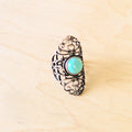 Blue turquoise ring in an antique copper filigree setting on a light wooden background