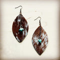 A pair of oval-shaped hair-on-hide leather earrings with brown and white speckled fur and a turquoise stone drop.