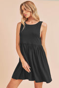 Woman wearing a minimalist black round neck mini tank dress in a summer setting