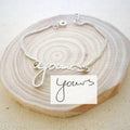 Custom name bracelet featuring an engraving of actual handwriting on a minimalist metal bar.