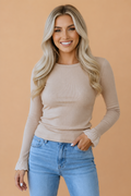 Close-up of the delicate lace cuff detail on a beige long-sleeve knit top.