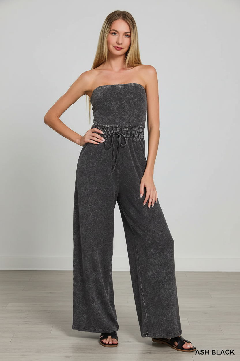 Woman wearing an ash black strapless jumpsuit against a plain background