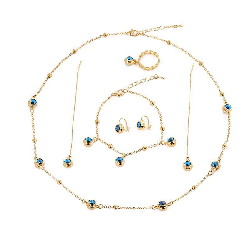 A five-piece jewelry set including a gold-tone necklace, bracelet, earrings, and ring with blue evil eye accents.