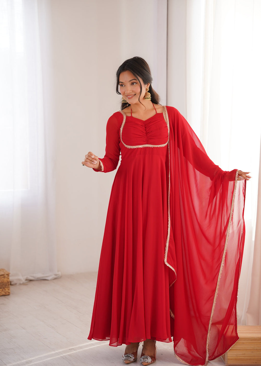 Model wearing a red faux georgette Anarkali gown with dori neck detail and matching dupatta.