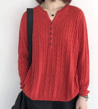 A woman wearing a button-front cable knit sweater in red and light pink.