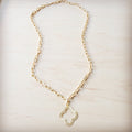 Matte gold quatrefoil pendant hanging on a matching gold-tone chain against a light wood background.