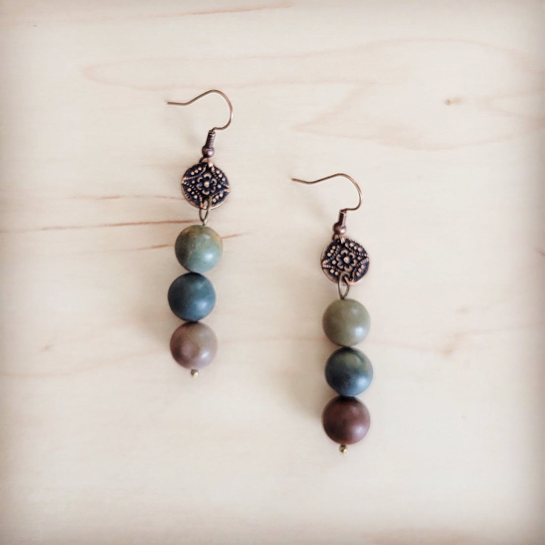 Frosted Picasso Jasper beads hanging from antique copper-tone floral discs on fish hook closures.