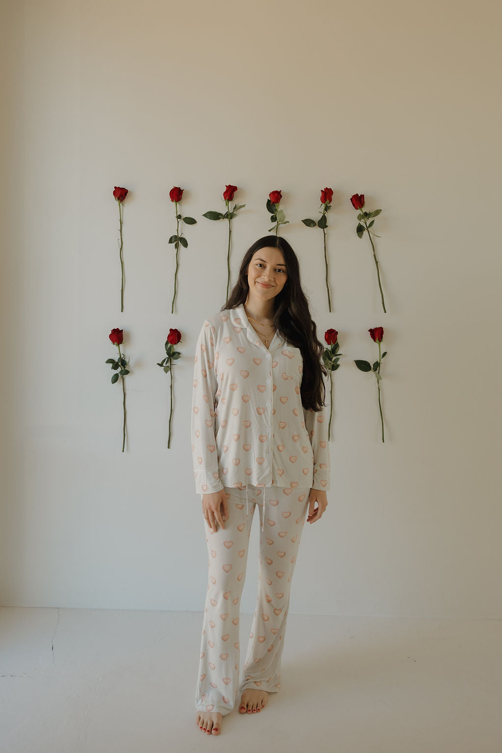 Woman wearing a grey bamboo lounge set with a heart print, including a long-sleeve button-up top and flared pants.