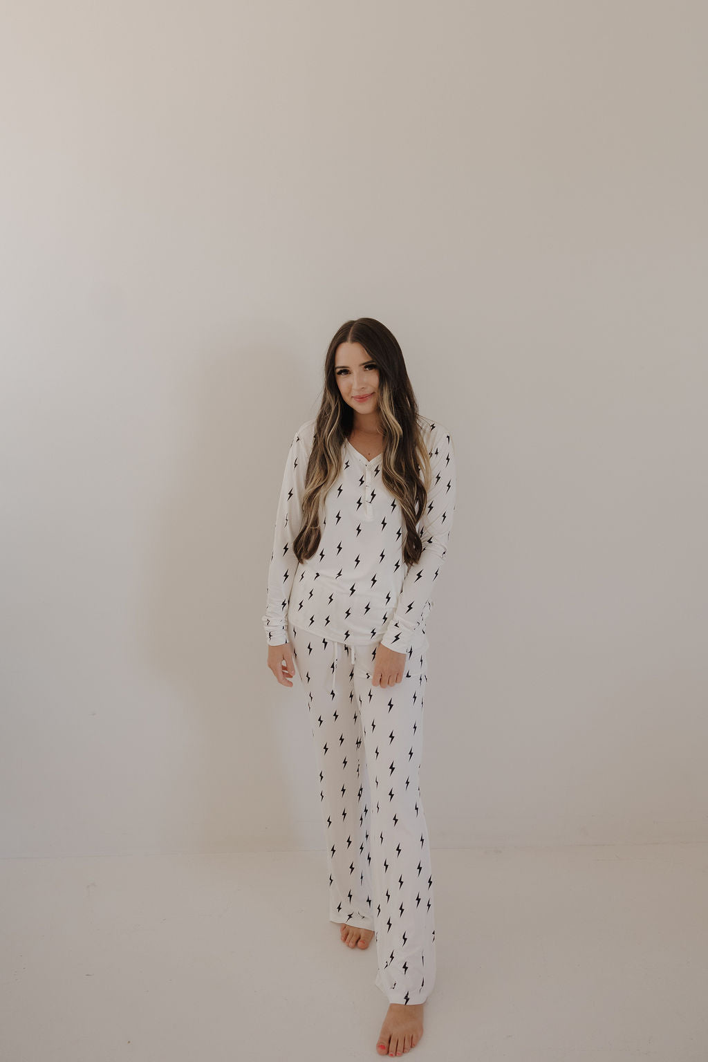 Women wearing long sleeve bamboo pajamas in a white and black lightning bolt print with front snaps
