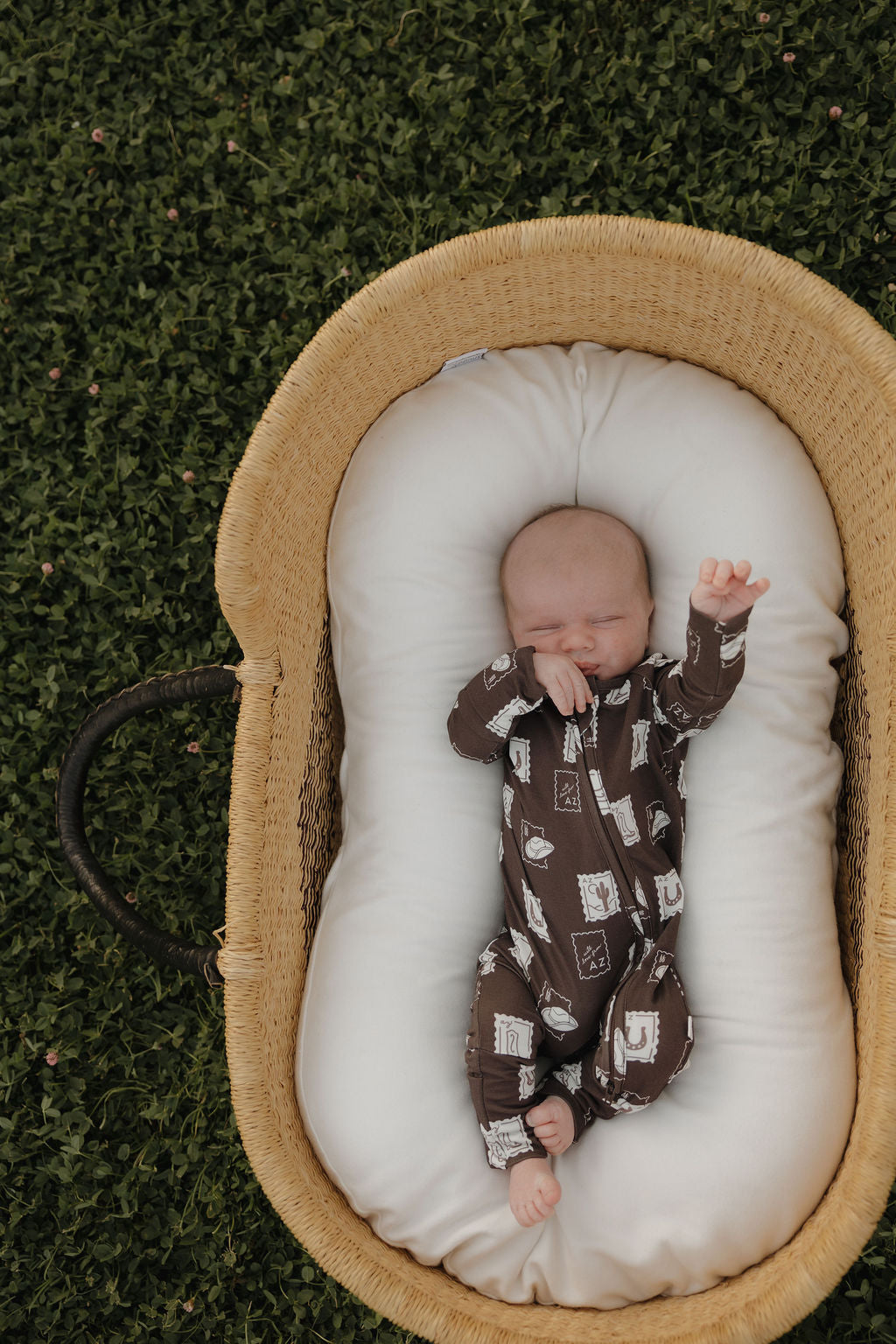 Baby wearing brown bamboo zip-up pajamas with a cute Arizona stamp-themed print.