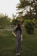 A woman wearing a brown lounge set featuring a With Love from AZ graphic print, consisting of a short-sleeve boxy tee and wide-leg pants, standing in a grassy area.