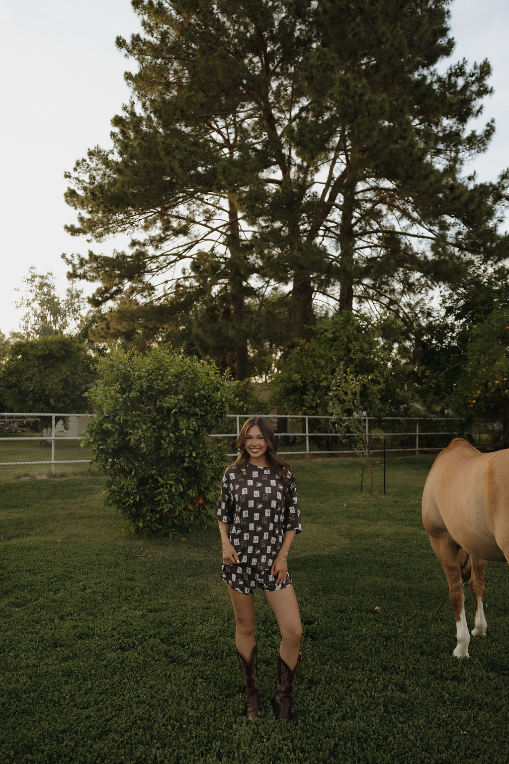 Woman wearing a charcoal grey bamboo short set with a white print standing in a green field