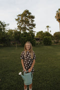 Girl wearing a brown bamboo short set with a "With Love from AZ" print while standing in a yard.