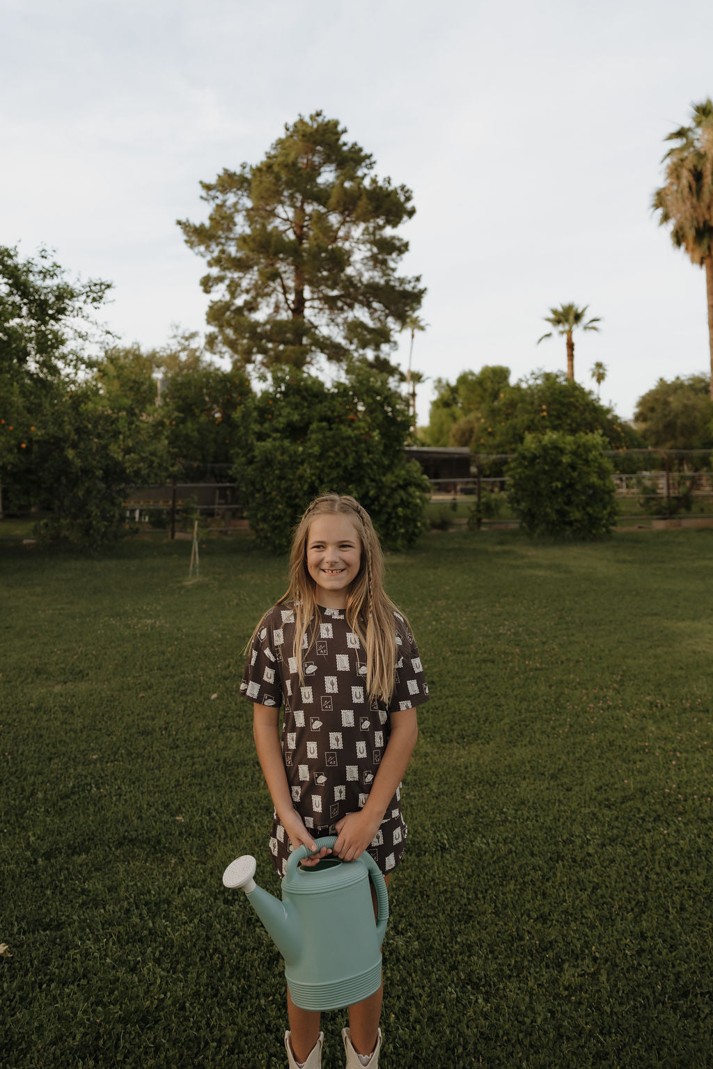 Girl wearing a brown bamboo short set with a "With Love from AZ" print while standing in a yard.
