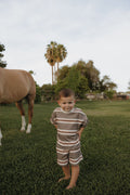 Young child wearing a comfortable Sedona Stripe cotton t-shirt and shorts set while standing outside in a grassy field.