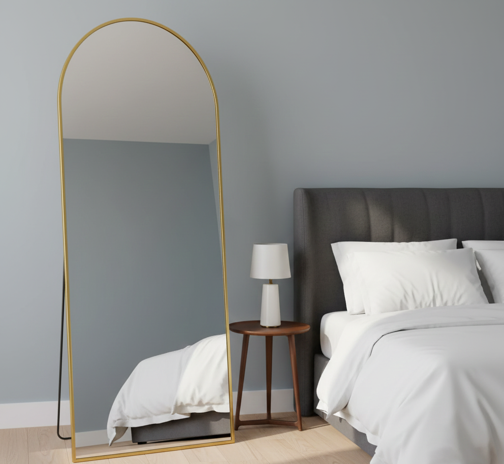Modern arched full-length floor mirror with metallic frame in a minimalist bedroom setting