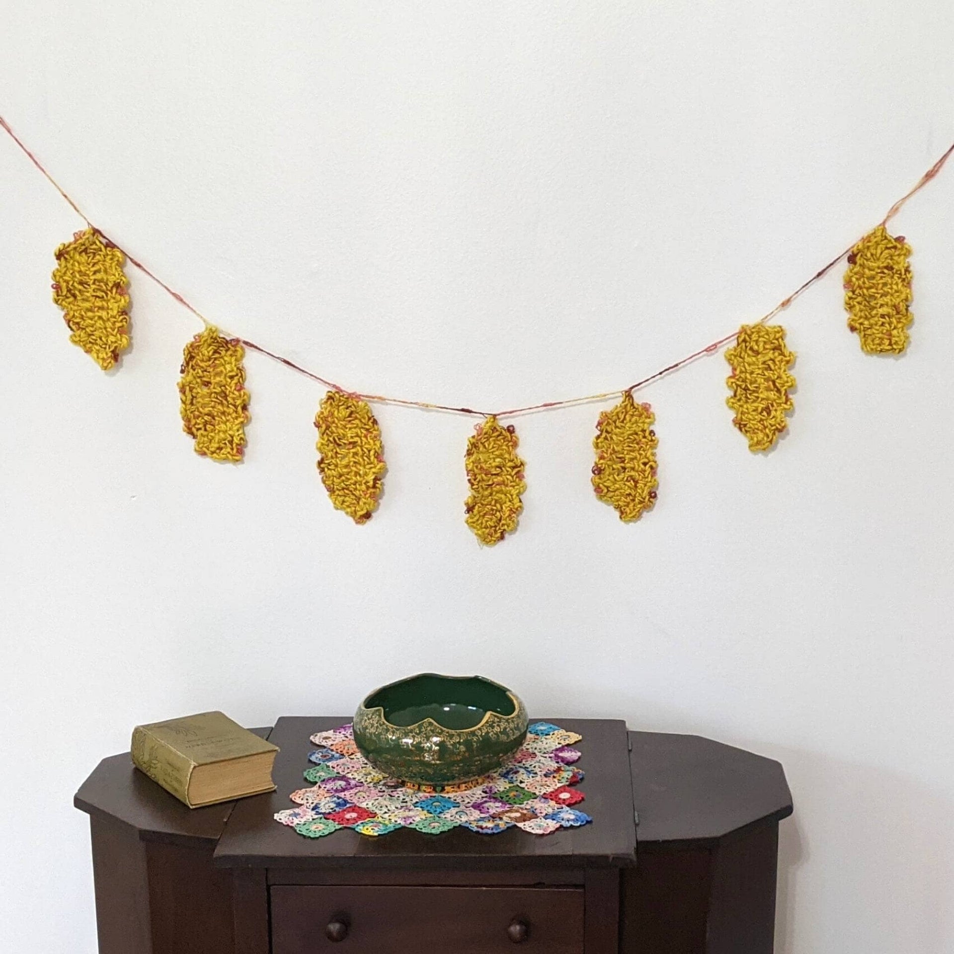 Close up of handmade festive fall leaves in yellow, rust, and brown hanging on a string for rustic bohemian home decor