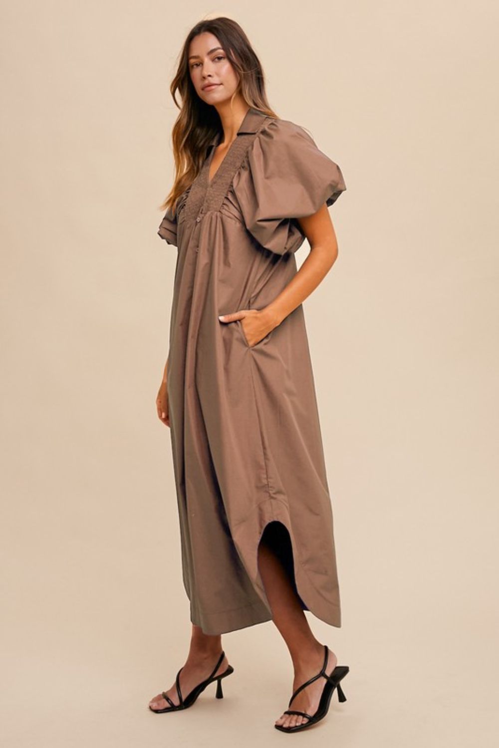 A woman wearing a feminine midi dress with a smocked bodice and dramatic puff sleeves.