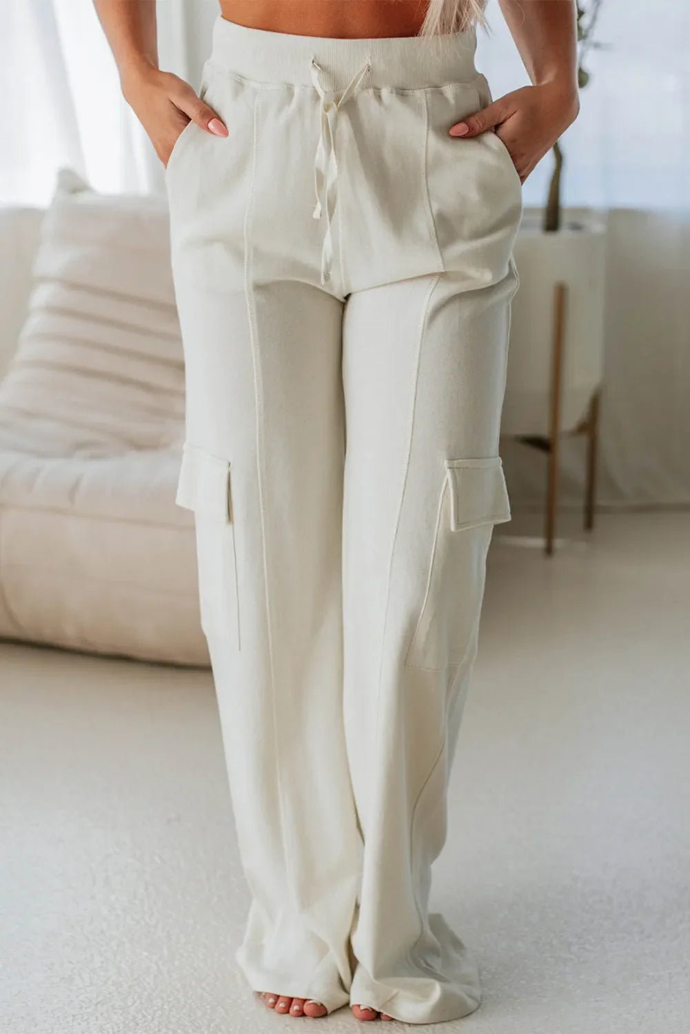 Model wearing off-white high waist cargo pants with drawstring detail and side pockets.