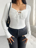 Front and back view of a woman wearing a white long sleeve top with a tied front detail