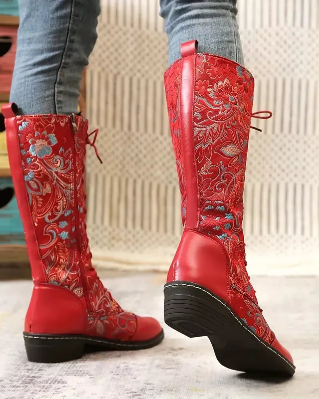 Red embroidered boots worn with gray jeans on a light background