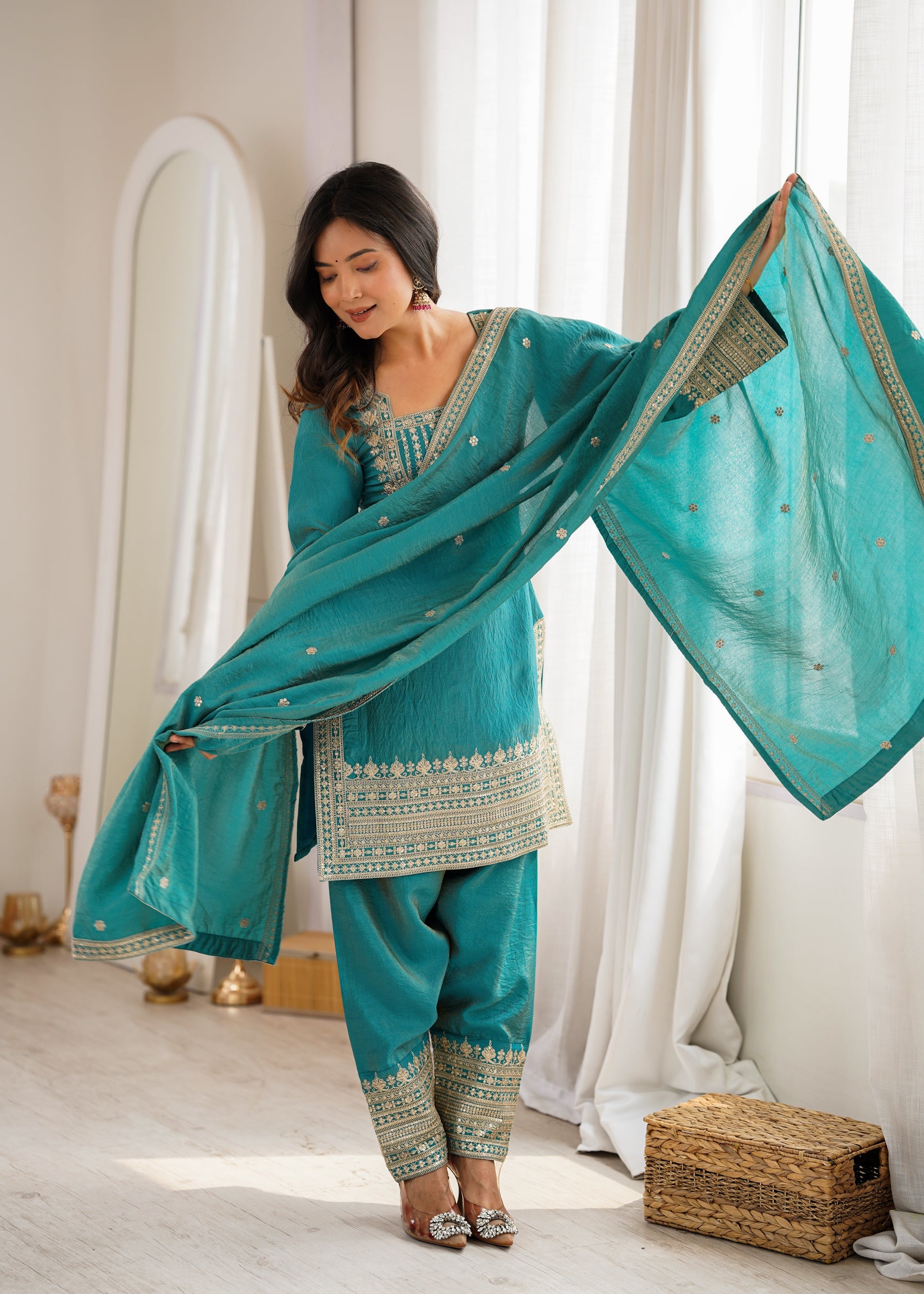 A teal Vichitra silk kurta with intricate gold embroidery and sequence work paired with a matching farshi salwar and dupatta.
