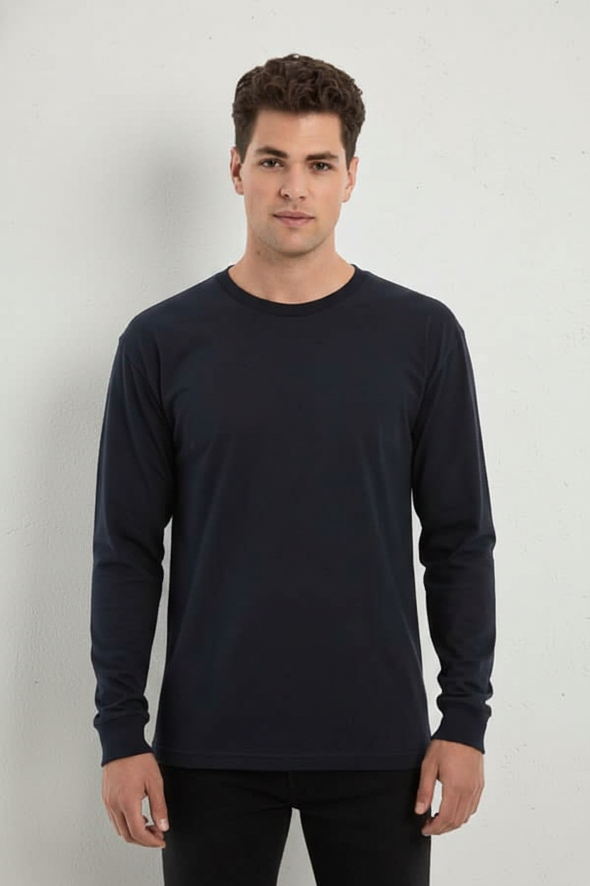 Model wearing a navy blue long sleeve crewneck t-shirt with cuffs in a studio setting