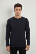 Model wearing a navy blue long sleeve crewneck t-shirt with cuffs in a studio setting