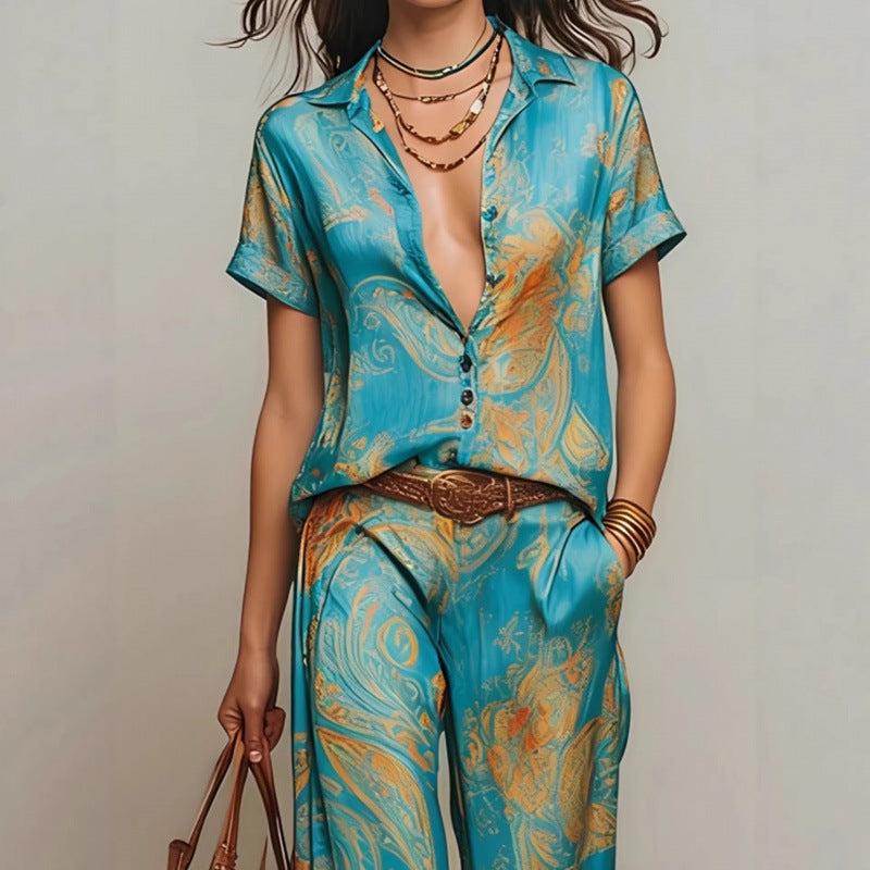 A woman wearing a vibrant blue and orange bohemian print two-piece set consisting of a button-down shirt and matching trousers.