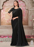 Model wearing a black traditional saree with heavy sequin embroidery and an unstitched blouse piece