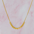 Gold chain necklace featuring a row of small heart charms on a pink marble background