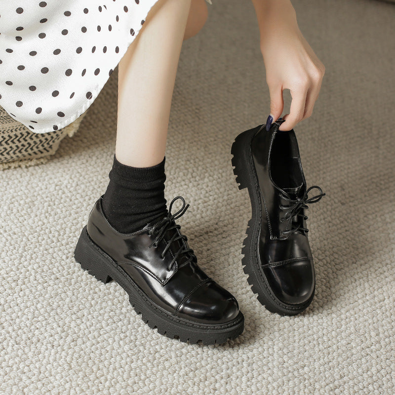 A pair of black women's retro platform oxford shoes with a chunky lug sole and lace-up closure.