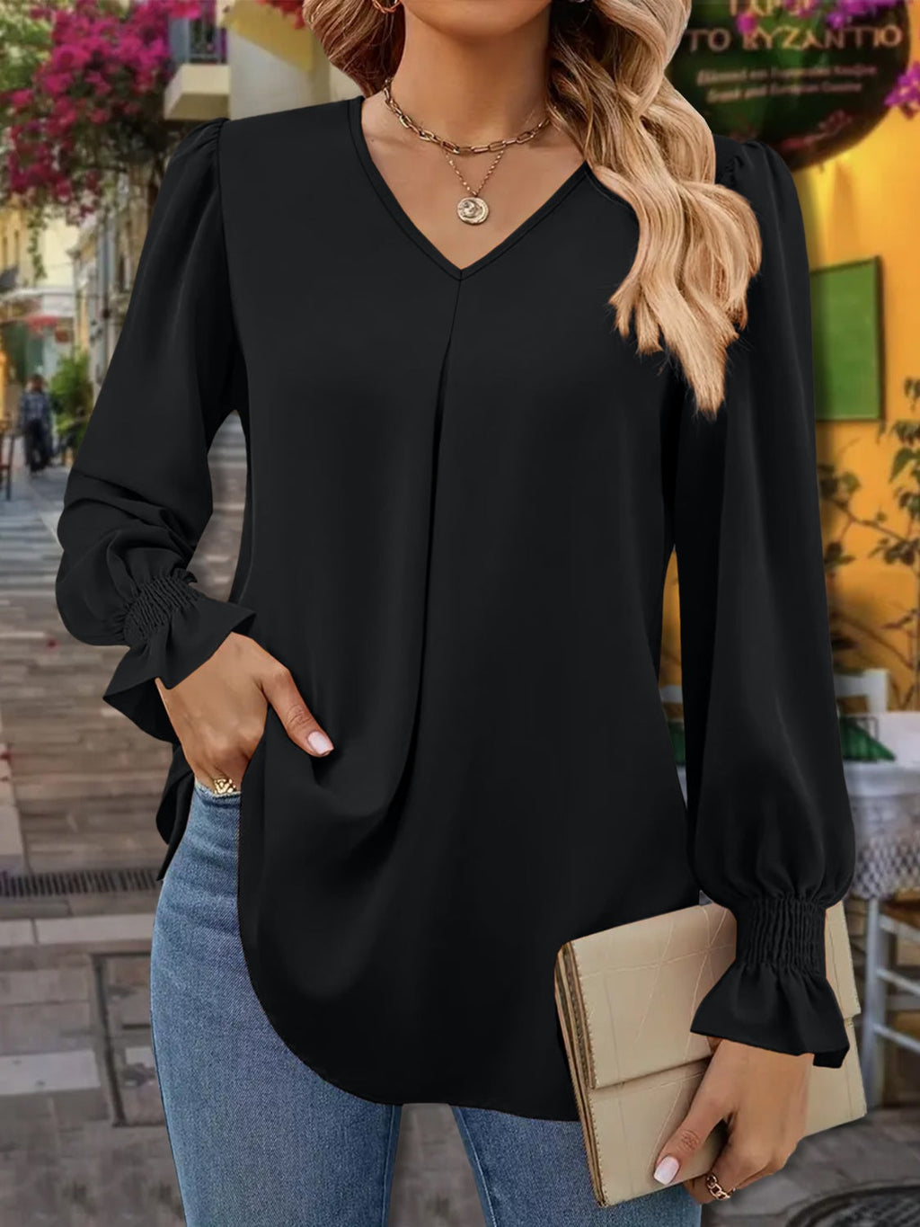 Woman wearing a V-neck blouse with flounce sleeves and ruffled detailing.