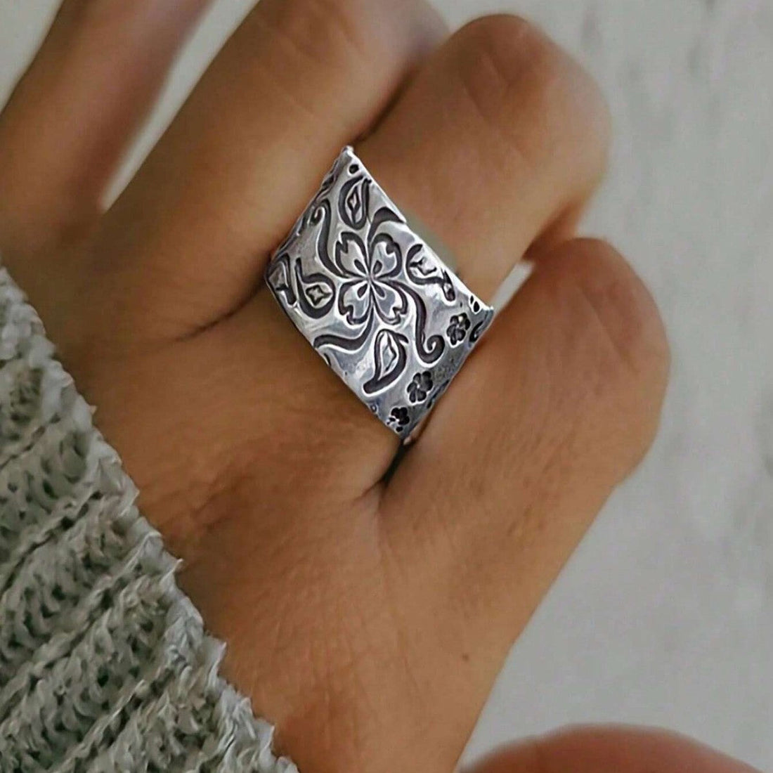 Antique silver statement ring with intricate floral carvings, viewed from the side to show detail.