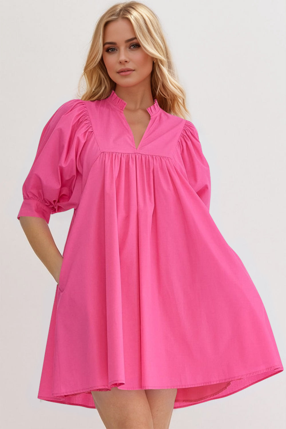 A woman wearing a pink puff sleeve mini dress with frill detailing in a sunny outdoor setting.