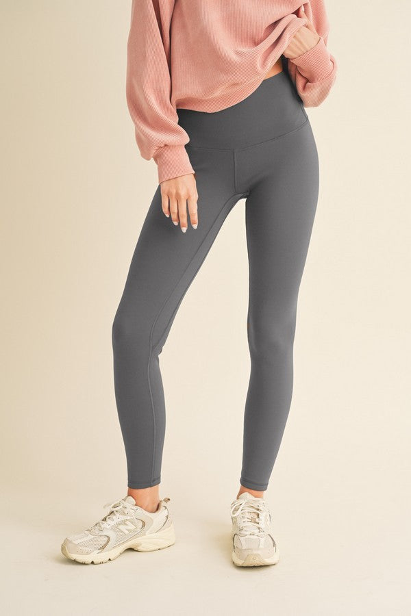 Model wearing charcoal grey high-waisted fleece-lined leggings paired with a pink sweater and sneakers