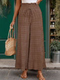 Woman wearing brown textured wide leg pants with a drawstring tie waist