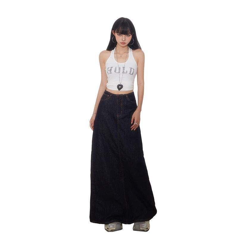 A woman wearing a high-waisted dark wash denim maxi skirt with a white tank top