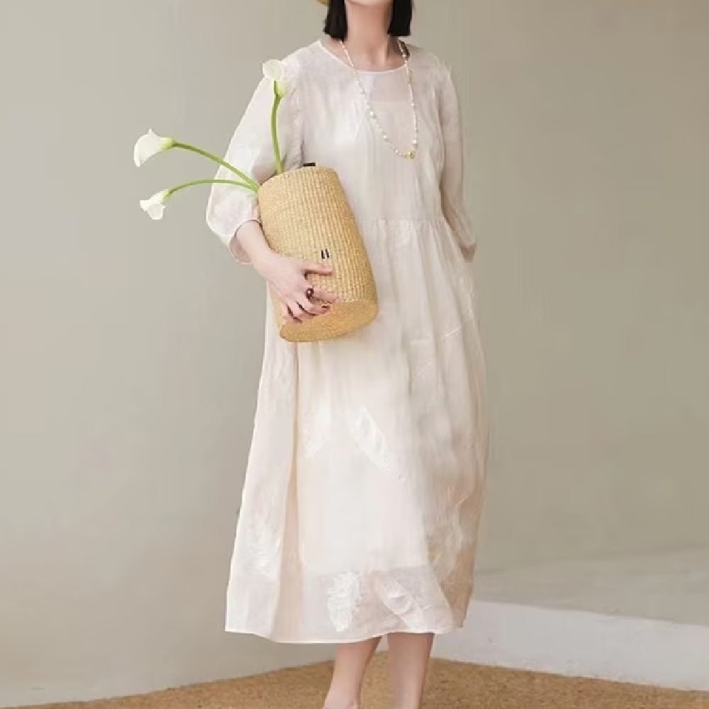 A woman wearing a relaxed, elegant white linen midi dress in a bright, minimalist setting.