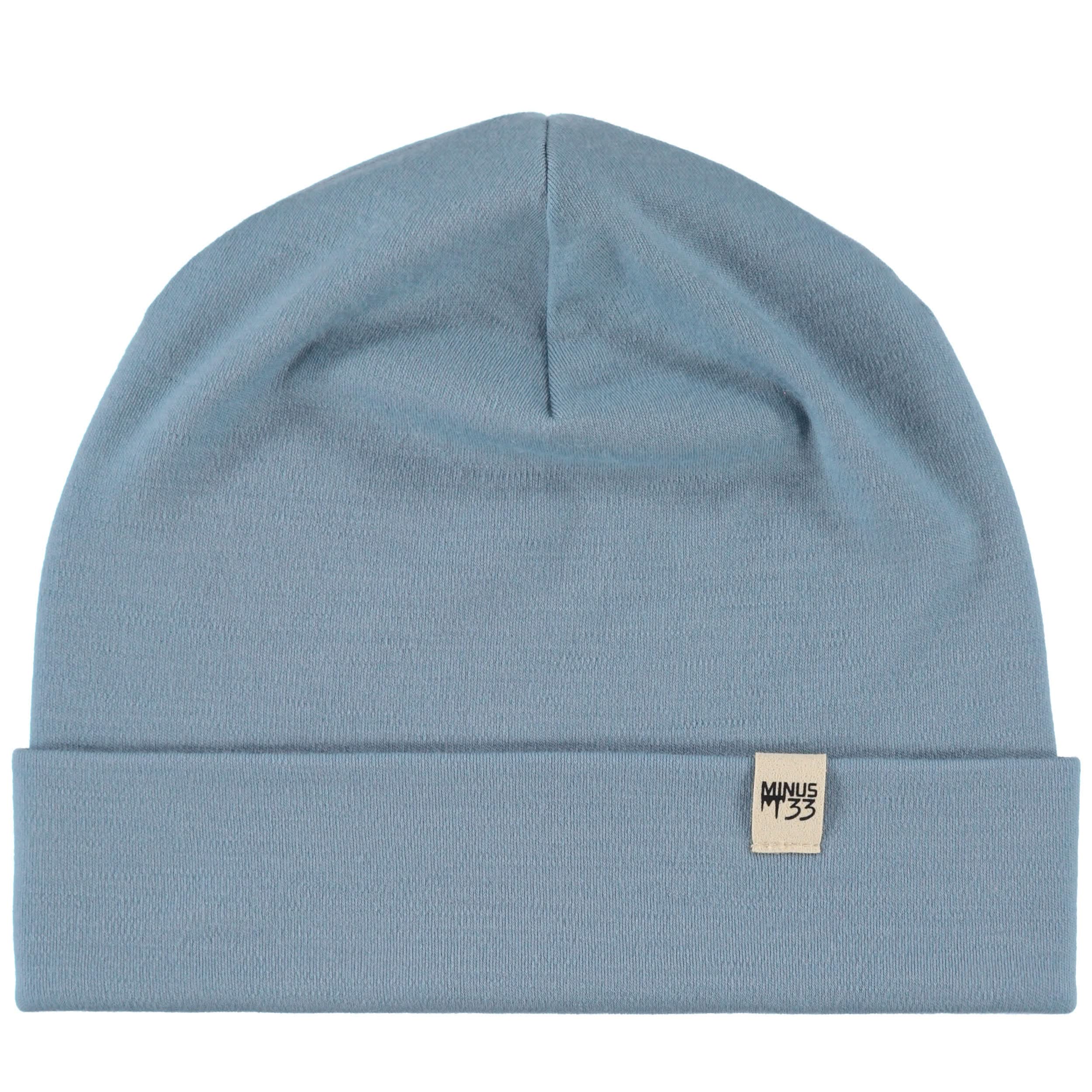 A solid knit Merino wool cuff beanie in grey, displayed in a minimalist outdoor setting