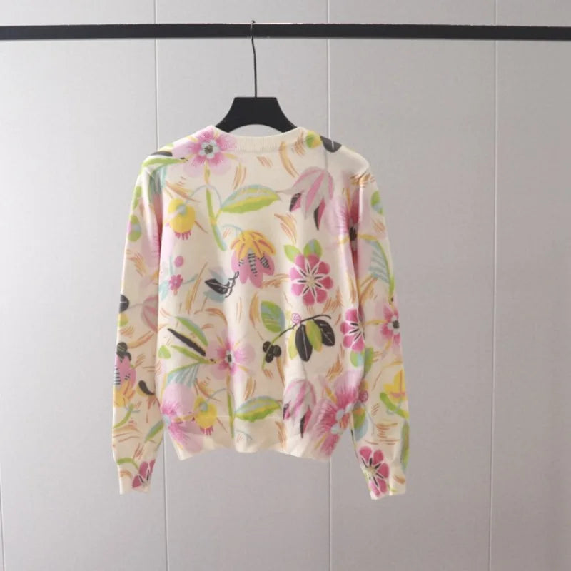 Women's cream knit sweater with vibrant floral print in pink, yellow, green, and blue, displayed on a hanger.