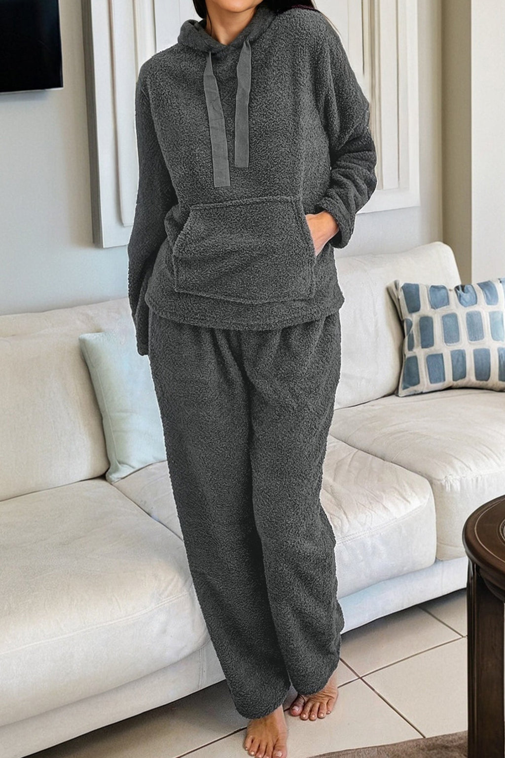 Woman wearing a charcoal grey fuzzy knit lounge set with a drawstring hoodie and straight-leg pants.