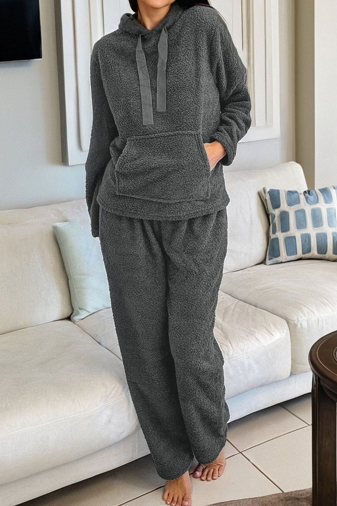 Woman wearing a charcoal grey fuzzy knit lounge set with a drawstring hoodie and straight-leg pants.